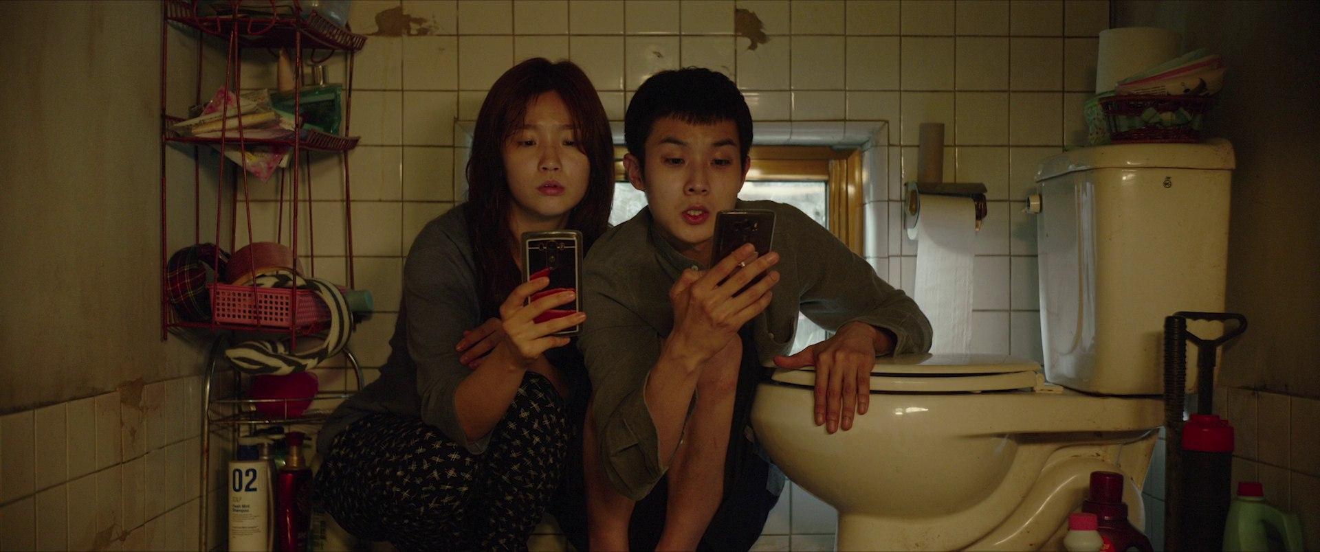 Ki-jung and Ki-woo in the semi-basement, hunched over their phones