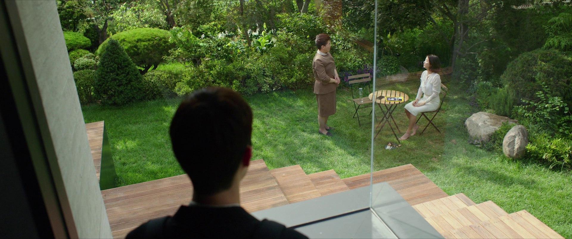 Ki-woo watching from the stairs as two women interact in the garden below